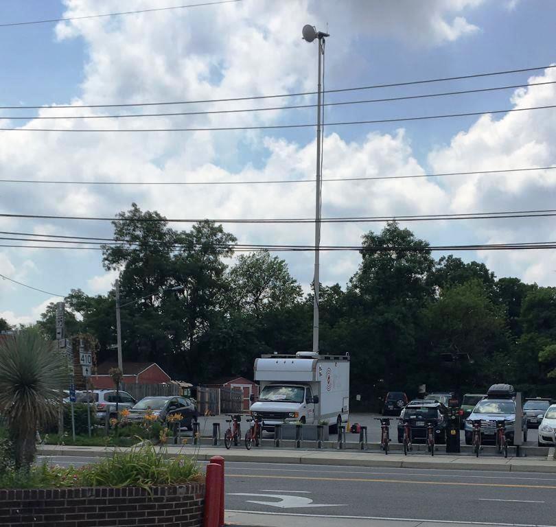 The van, with its mast extended to full height, is seen in a parking lot at the parade stepping-off point.